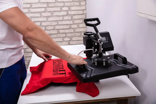 Man printing on t shirt in workshop