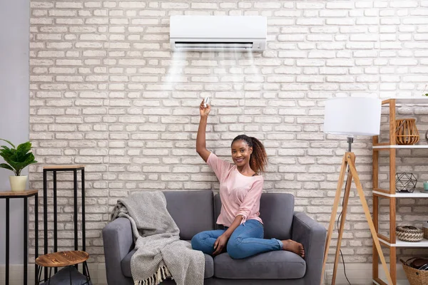 Young African Woman Switching Air Conditioner Remote Control Home — 스톡 사진