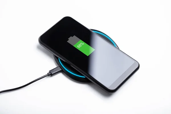 Smartphone Charging On A Wireless Charging Pad Over White Desk