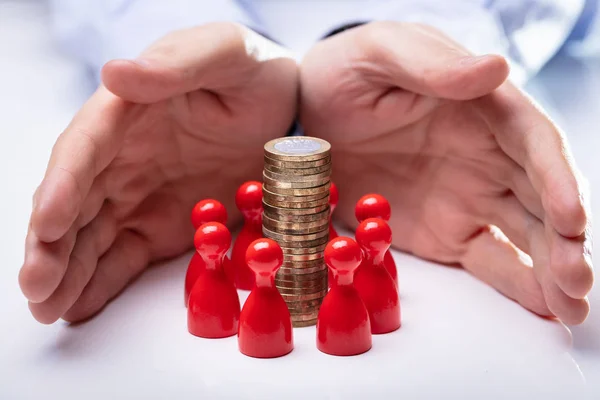 Close Hands Protecting Coin Stack Surrounded Red Figures White Desk — Stock Photo, Image