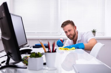 Janitor cleaning white desk in modern office clipart