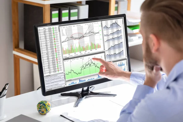 オフィスの画面上のグラフを見て株式市場ブローカーの側面図 — ストック写真