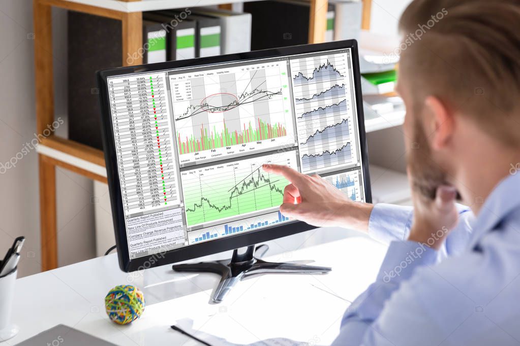 Side view of stock market broker looking at graphs on screen in office