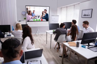 Ofiste video konferans sırasında ekrana bakan bir iş adamının arkadan görünümü