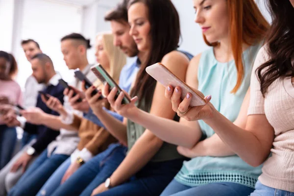 Jóvenes Multiétnicos Inclinados Cerca Mesa Fila Usando Smartphone —  Fotos de Stock