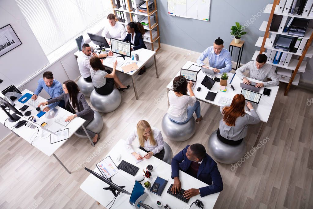 Group Of Multi-ethnic Businesspeople Sitting On Fitness Ball Having Discussing While Working In Office