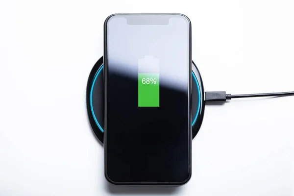 Smartphone Charging On A Wireless Charging Pad Over White Desk