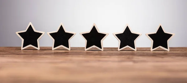 Close-up Of Five Star Rating Icon In Row On Wooden Desk