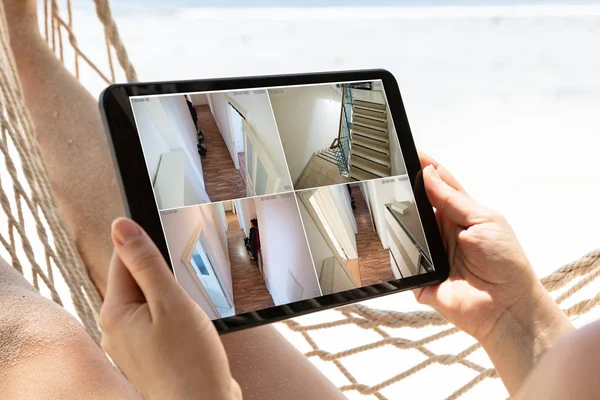 監視カメラを見てハンモックに横たわっている女性 ビーチでのデジタルタブレットのライブビュー — ストック写真
