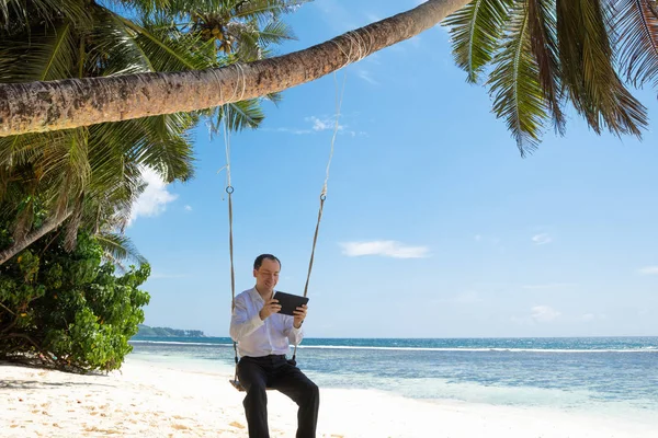 Muž Sedící Houpačce Použití Digitálního Tabletu Písečné Pláži Poblíž Idylické — Stock fotografie