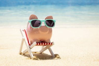 Sahilde Kum üzerinde Minyatür Şezlong Üzerinde Turkuaz Güneş Gözlüğü ile Pembe Piggybank Close-up