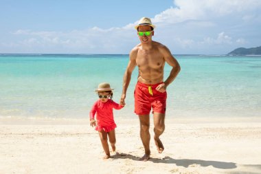 Mutlu baba giyen güneş gözlüğü ve şapka koşu Ile onu kız üzerinde pastoral plaj