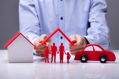Hand Holding Roof Over Family Near Car And House clipart