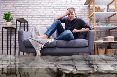 Oturma odasındaki koltukta oturan üzgün genç adam sular altında kaldı.