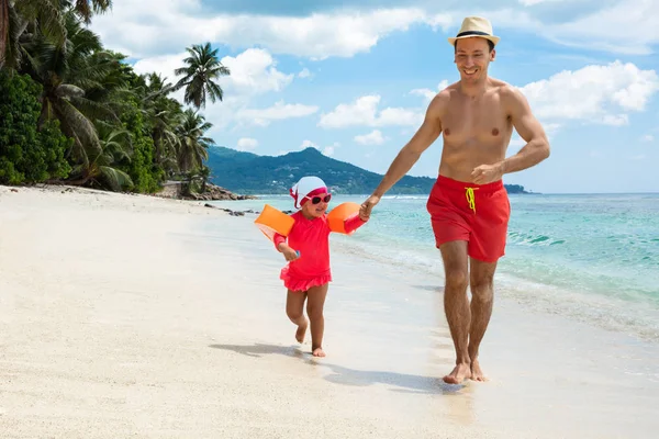 浜で娘と一緒に走る帽子をかぶった笑顔の青年の肖像 — ストック写真