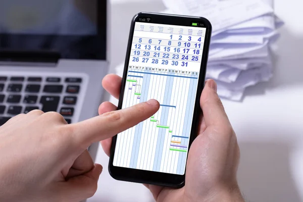 Close Van Een Persoon Hand Analyseren Gantt Grafiek Mobiele Telefoon — Stockfoto