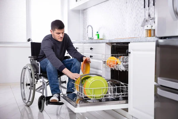 Joven Hombre Discapacitado Sentado Una Silla Ruedas Organizando Placas Lavavajillas — Foto de Stock