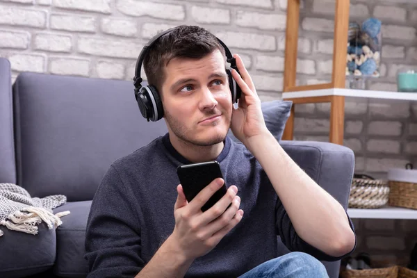 Homem Feliz Apoiando Sofá Enquanto Ouve Música Com Fones Ouvido — Fotografia de Stock