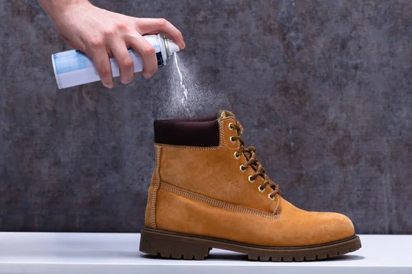 Menschliche Hand Sprüht Deo Auf Stinkende Schuhe Über Weißem Schreibtisch — Stockfoto