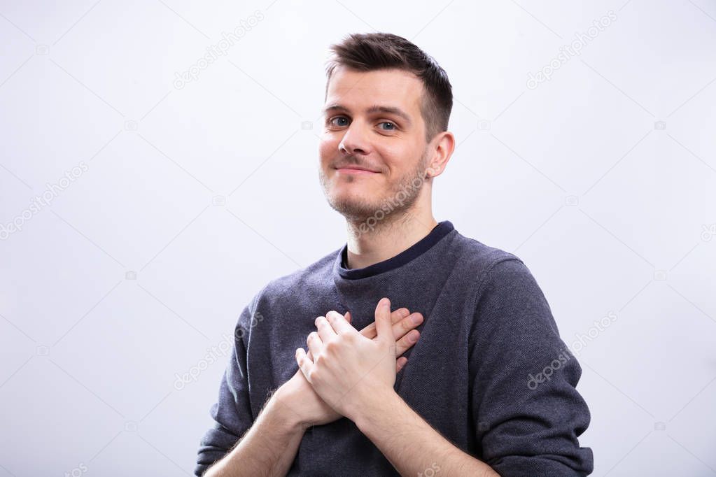 Portrait Of Smiling Man With His Hand Clasp Day Dreaming Against White Background