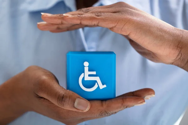 Zbliżenie Ludzkiej Dłoni Chroniącej Niebieski Sześcienny Blok Niepełnosprawną Ikoną Handicap — Zdjęcie stockowe