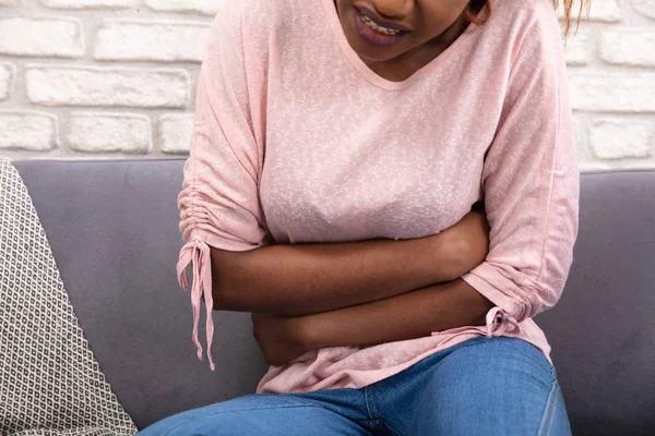 Mujer Joven Sentada Sofá Que Sufre Dolor Estómago Casa —  Fotos de Stock