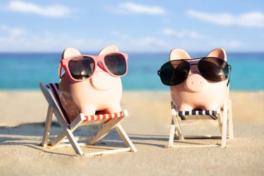 Plajda Tatil keyfini Şezlong üzerinde Güneş Gözlüğü ile İki Piggybanks Close-up