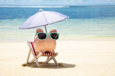 Plajda Kum Üzerinde Şezlong Üzerinde Güneş Gözlüğü ve Şemsiye ile Pembe Piggybank