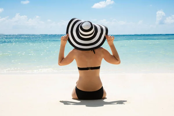 Rear View Of The Young Woman In Bikini And Hat On The Tropical Beach