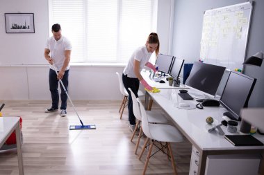 İki gülümseyen genç hizmetli büro temizlik ve ofis zemin mopping