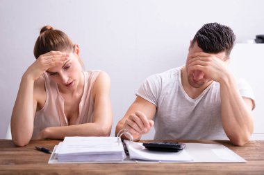 Vurgulayan genç çift ahşap masa üzerinde fatura bakıyor