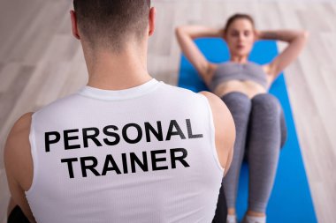 Kişisel antrenör genç kadın egzersiz Yoga mat yaparak bakarak