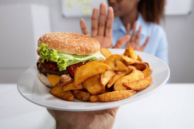 Genç kadın hamburger ve patates kızartması plaka üzerinde reddediyor