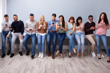 Akıllı Telefon Kullanarak Masanın Yakınında Eğilen Çok ırklı Gençler 