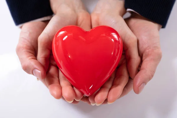 Close Mão Casal Segurando Coração Vermelho Sobre Fundo Branco — Fotografia de Stock