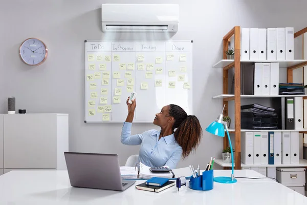 Young Businesswoman Operating Air Conditioner Remote Controller Office — Stock Photo, Image