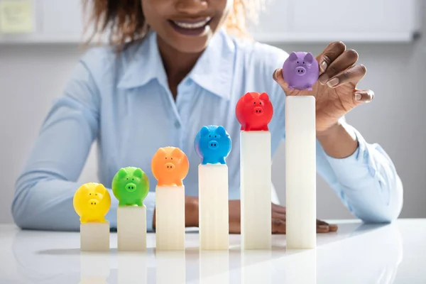 Рука Предпринимательницы Размещает Разноцветный Свинобанк Растущем Графике Офисе — стоковое фото