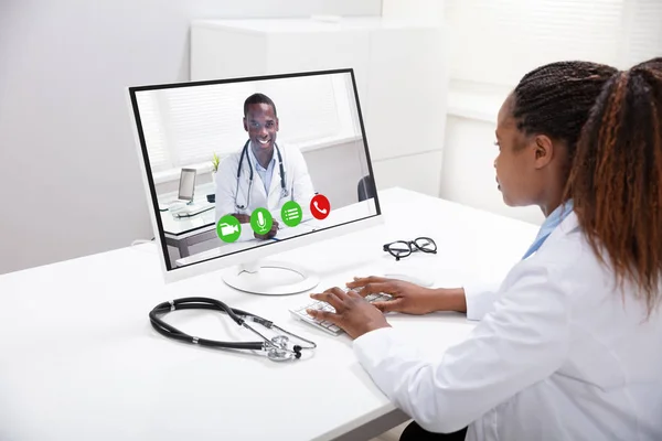 Female Doctor Video Conferencing With Happy Male Colleague On Computer Over Desk