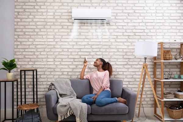 Mujer Africana Joven Encendiendo Aire Acondicionado Con Control Remoto Casa —  Fotos de Stock