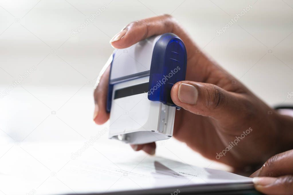 Close-up Of Businesswoman Putting Stamp On Documents In The Office