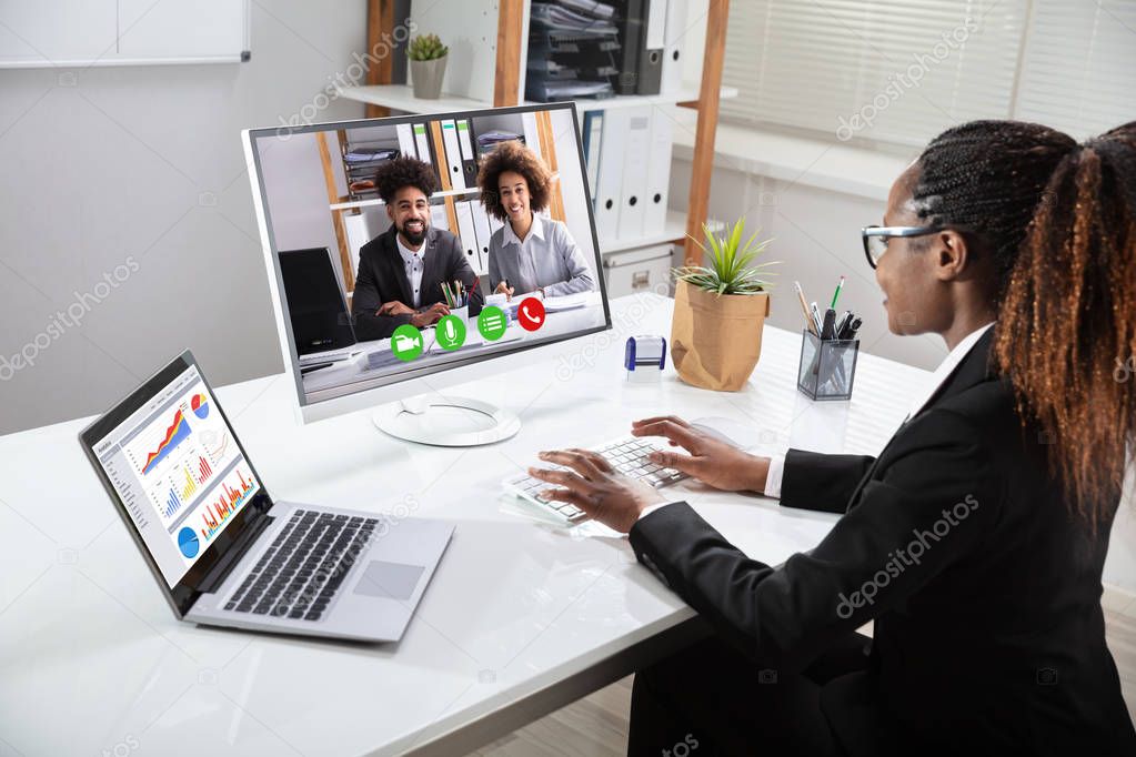 Smiling Young Businesswoman Videoconferencing With Her Colleagues On Computer Near Laptop