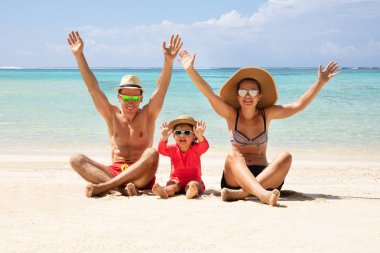 Mutlu aile onların eller sahilde tatil zevk kum üzerinde oturan yükseltmek