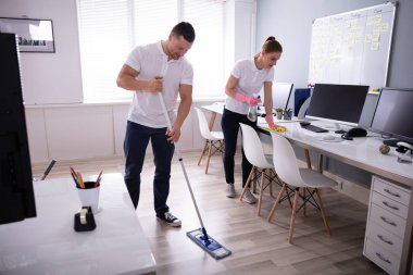 İki gülümseyen genç hizmetli büro temizlik ve ofis zemin mopping