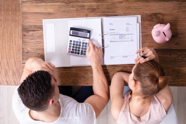 Vurgulayan genç çift ahşap masa üzerinde fatura bakıyor