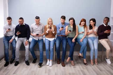 Akıllı Telefon Kullanarak Masanın Yakınında Eğilen Çok ırklı Gençler 