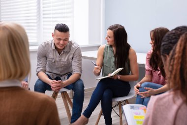 Smiling Men Looking At Their Male Friend While Discussion clipart