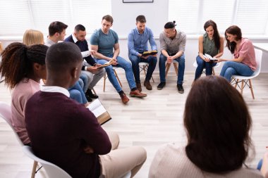Kutsal Kitap okuyan çok ırklı bir grup genç.