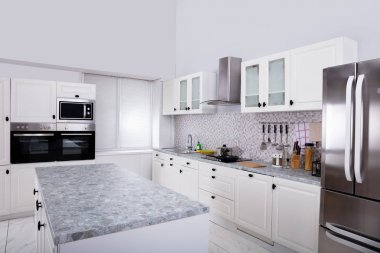 Mikrodalga fırın ve buzdolabı olan modern beyaz mutfağın içi.