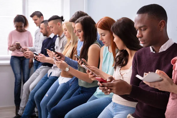 Jóvenes Multiétnicos Inclinados Cerca Mesa Fila Usando Smartphone —  Fotos de Stock