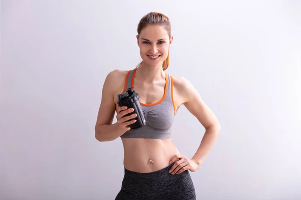 Porträtt Leende Fitness Kvinna Innehav Protein Shaker Flaska Mot Grå — Stockfoto